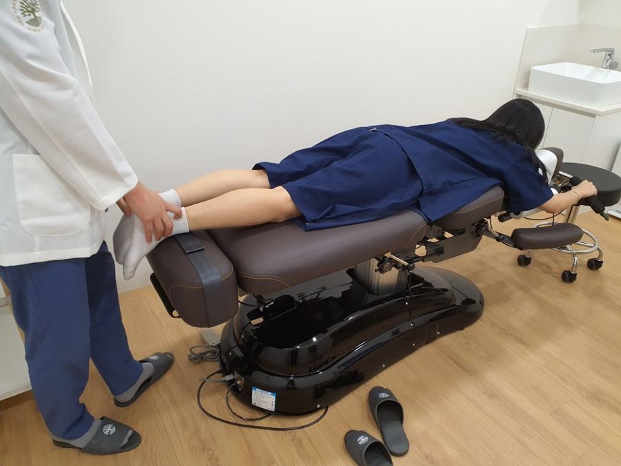 엎드린 환자의 다리를 교정하는 의료진